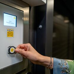 A woman holds an RFID chip up to the sensor on a control panel