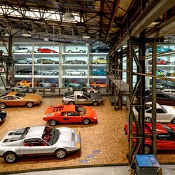 A wall-mounted shelf full of cars in a museum