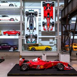 A wall-mounted shelf full of cars in a museum
