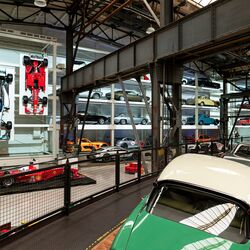 A wall-mounted shelf full of cars in a museum