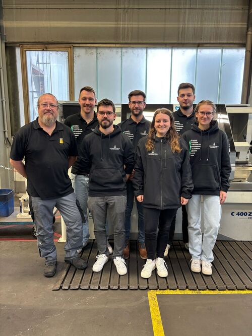 Seven people in a group photo in the production hall