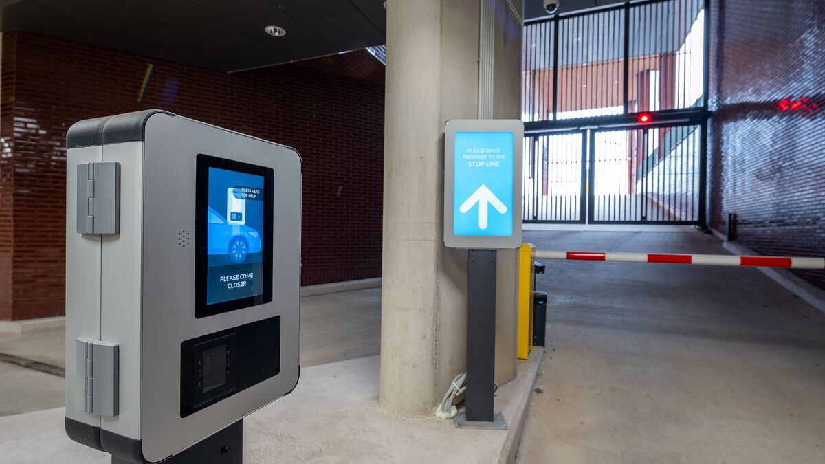 Wyjazd z nowoczesnego systemu parkingowego z terminalem dostępu, cyfrowym systemem informacji dla kierowców i automatycznym szlabanem.